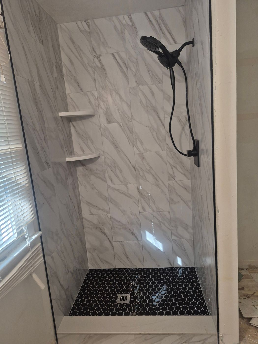 Marble-look shower with black hex floor